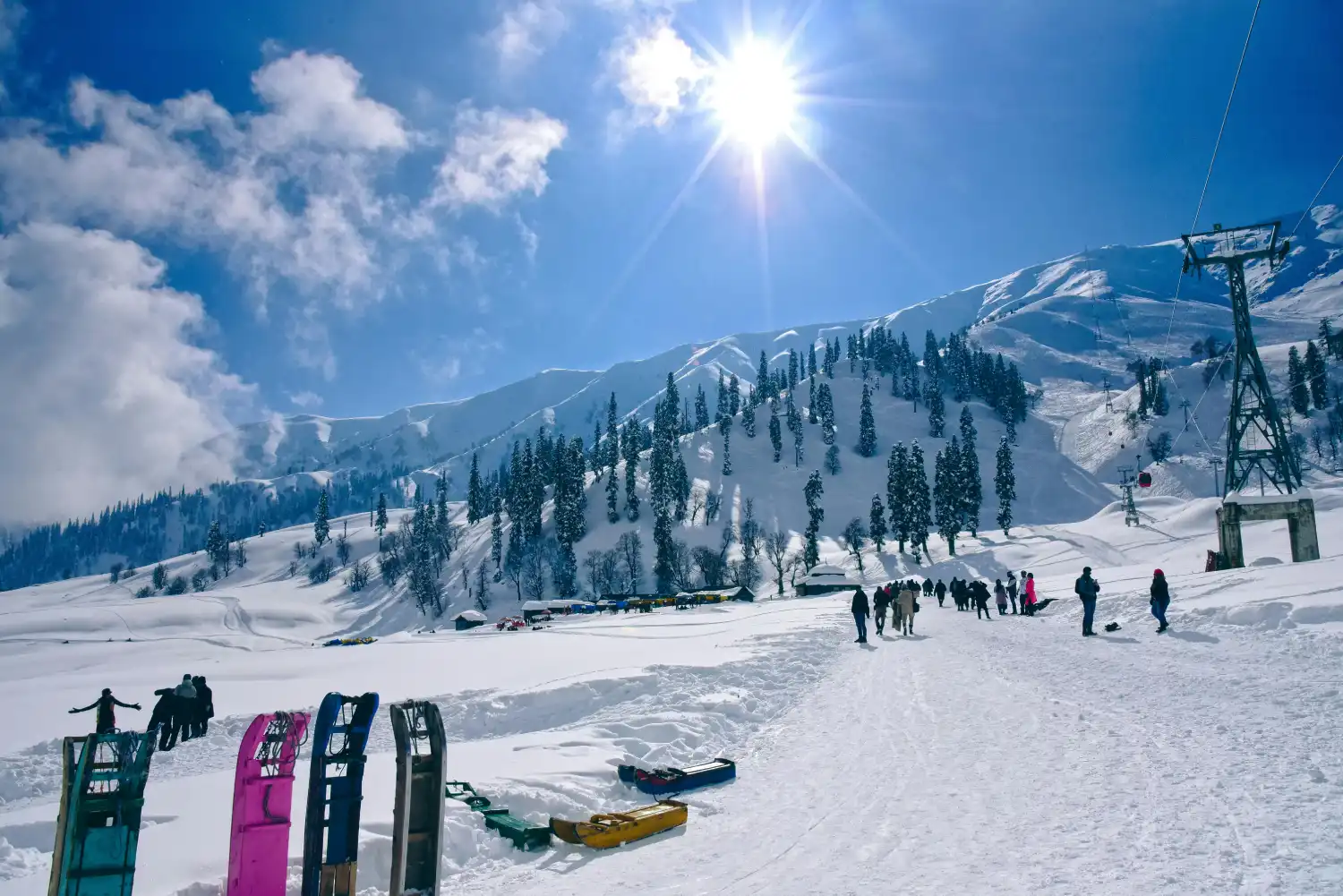 Tourists enjoying snowfall in Kashmir surrounded by snowy mountains and winter landscapes.